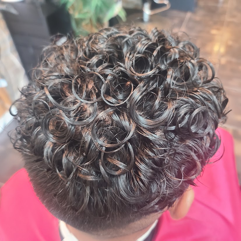After the first men's perm result: defined dark curls on top, viewed from above