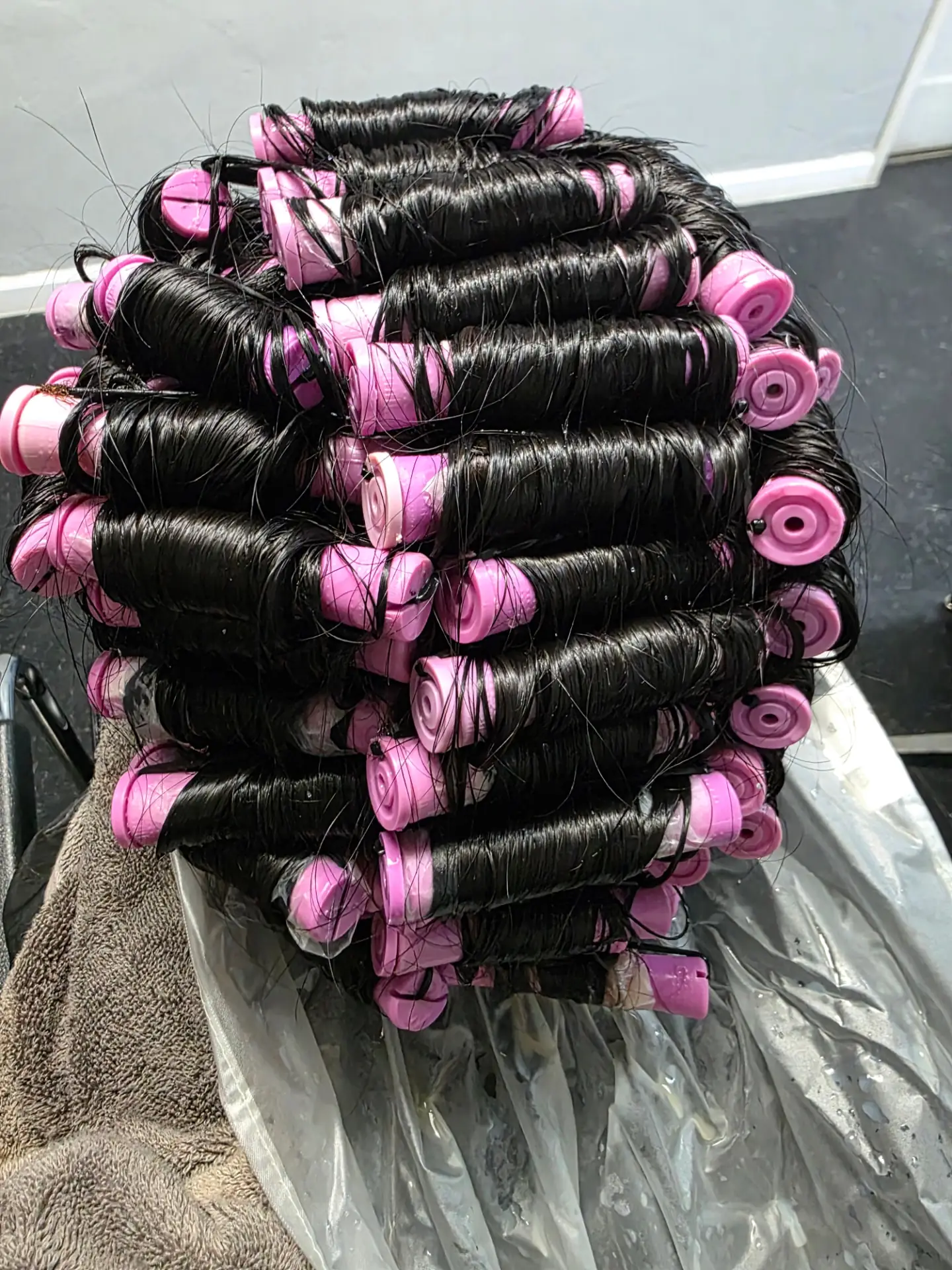Before a women's perm: long dark hair wrapped around pink rods during the process